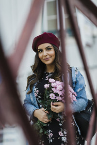 Portrait confident young woman in beret holding flower bouquet