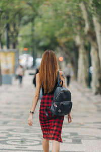 Young woman with backpack walking in urban park