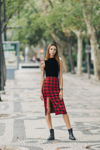 Portrait confident stylish young woman wearing checked skirt in urban park
