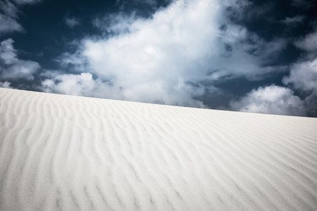 Pattern over sand dune below clouds in sky