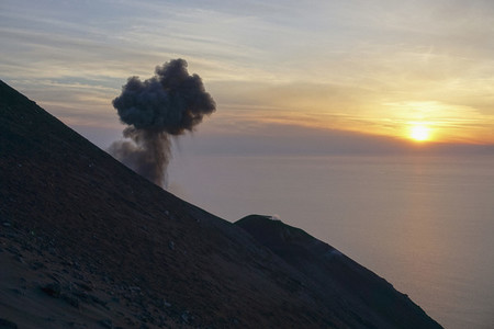 Ash plume rising along tranquil sunset ocean view