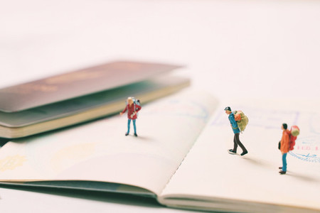 Miniature people figures with backpack walking and standing on p