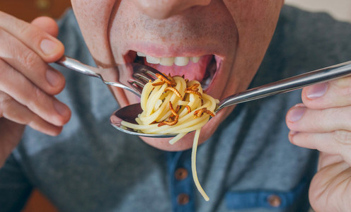 Man eating spaghetti with worms