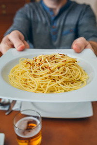 Hands of man showing spaghetti with worms dish