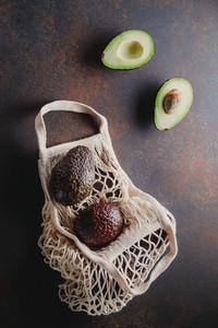 Avocado hass in a white eco net bag on a table