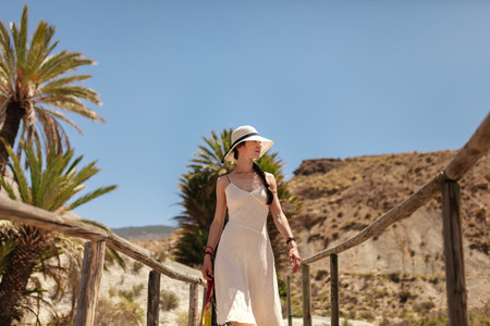 Woman wearing dress walking on a wooden bridge in the desert