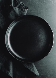 Top down view on an empty ceramic black plate on a dark background  Food or eating concept dark mockup