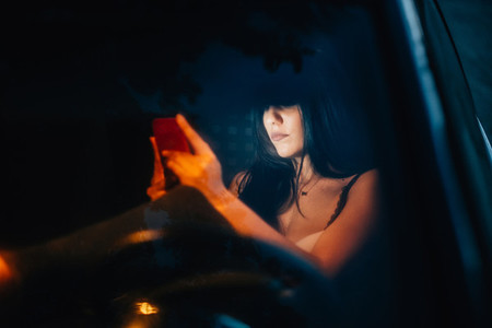 Young woman inside a car using her smartphone