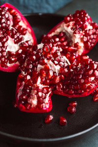 Close up view on a ripe pomegranate in a black plate on a dark background