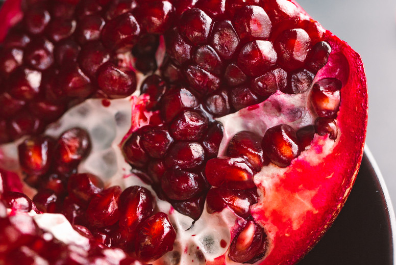 Close up view on a ripe pomegranate in a black plate on a dark background.