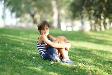 Little girl eight years old sitting on the grass outdoors
