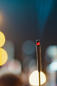Incense stick burns against blurred candle lights  Macro photography