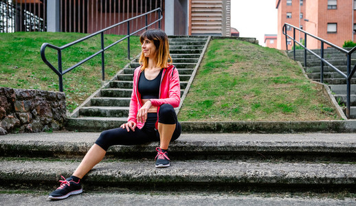 Female athlete posing sitting on the stairs outdoors
