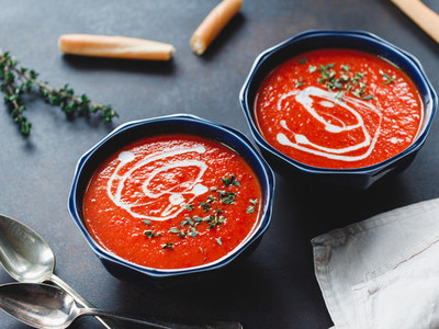 Two portions of red tomato cream soup in bowls with spices
