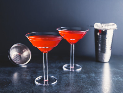 Red cocktail with lime in Martini glass on a table