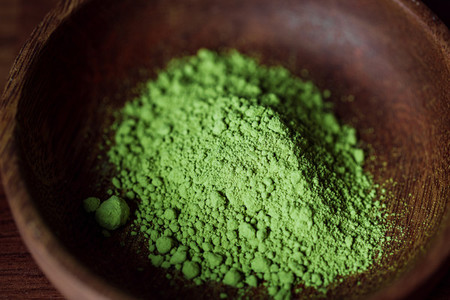 Macro photography of matcha green tea powder in a wooden bowl