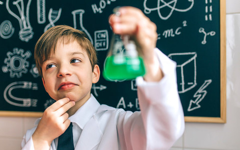 Thoughtful boy dressed as chemist with flask