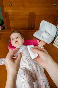 Hands of mother pouring serum to clean baby eyes