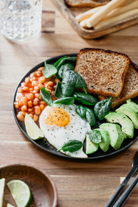 Fried egg  avocado  toasts  beans and fresh spinach  Healthy eating concept