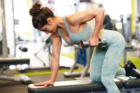 Woman working on her triceps and biceps in a gym with dumbbells