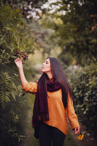 Young woman walking through the forest wearing a orange sweater