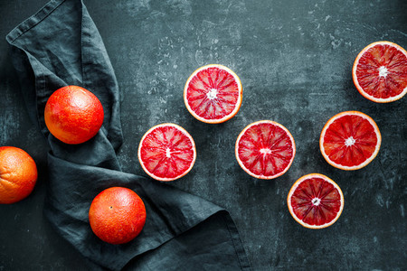 Flat lay food composition with blood oranges on a dark blue background