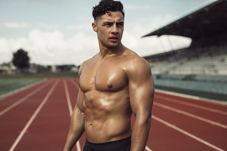Muscular man relaxing after a run on the track
