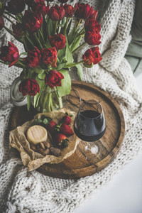 Glass of red wine  snacks and tulips on wooden board