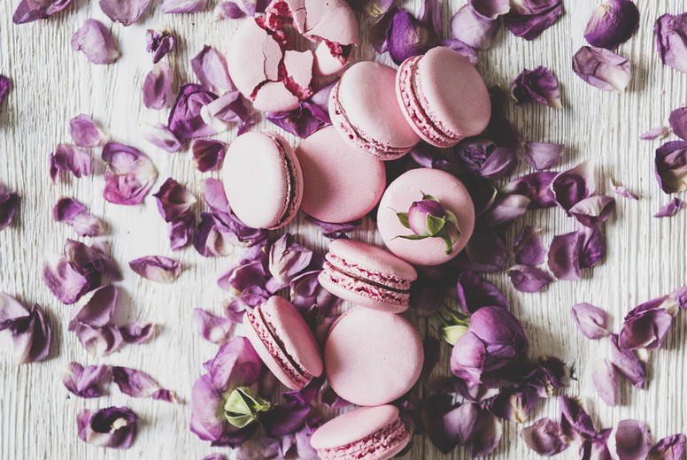 Sweet macaron cookies and rose buds and petals, vertical composition