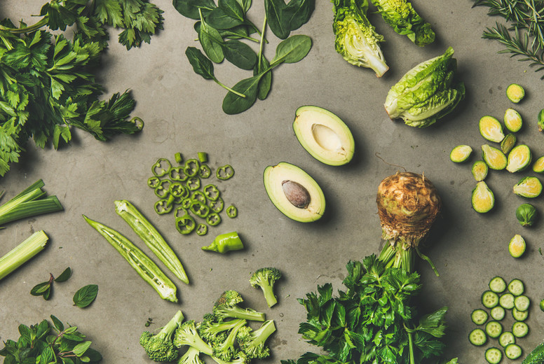 Flat-lay of whole and cut green vegetables and edible herbs