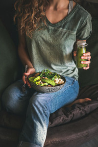 Woman sitting and holding healthy superbowl and smoothie