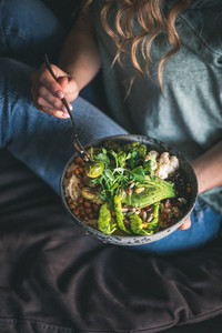 Woman sitting and eating vegan dish with himmus and avocado