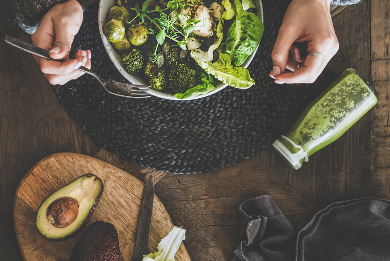 Flat-lay of healthy dinner vegetarian superbowl, smoothie and womans hands