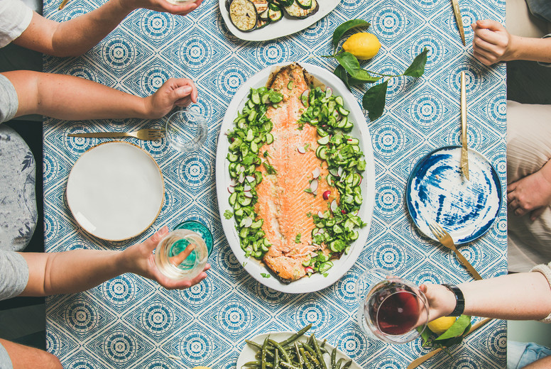 Mediterranean style dinner with cooked salmon, bread, lemonade, square crop