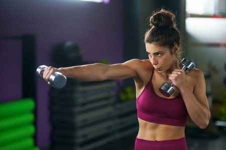 Sporty woman punching and boxing with dumbbells