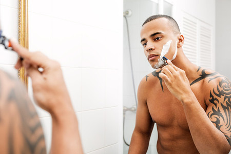 Mixed race person shaving face