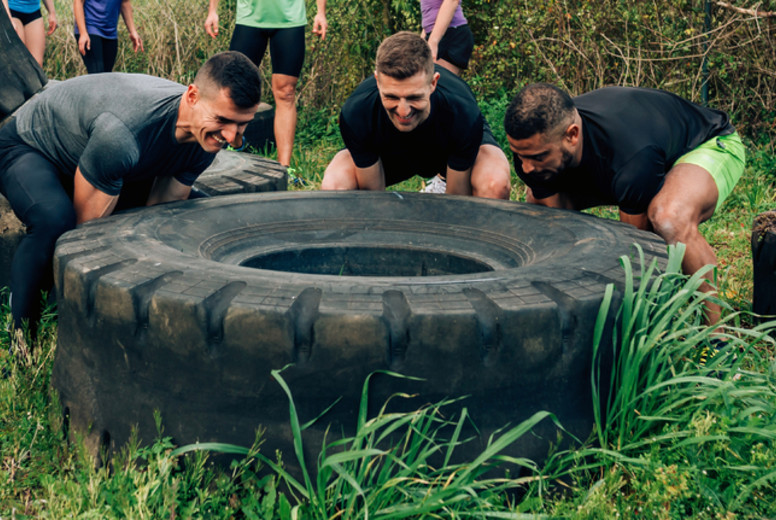 Participants in an obstacle course turning a wheel