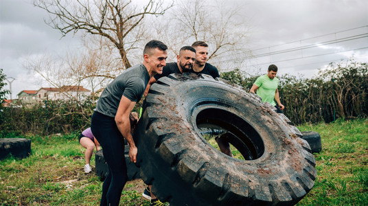 Participants in an obstacle course turning a wheel