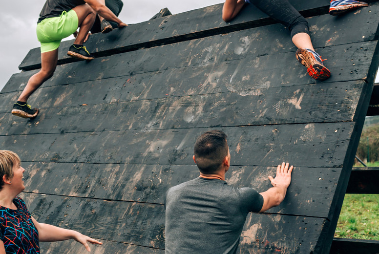 Participants in obstacle course climbing pyramid obstacle