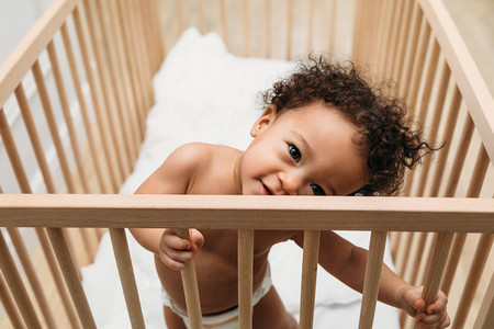 Cute baby boy standing in a crib