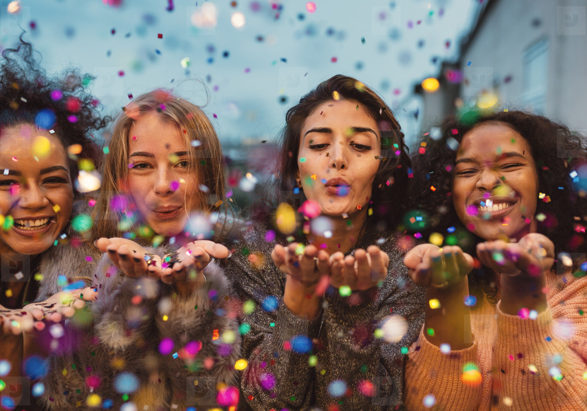 Young women blowing confetti