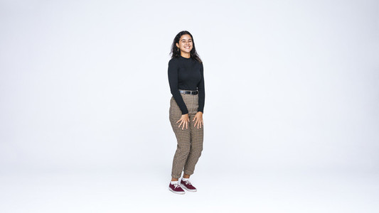 Smiling young woman standing on white background