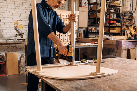 Senior male carpenter drilling