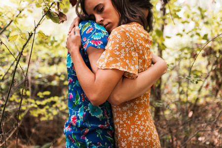 Two hugged women surrounded by forest plants