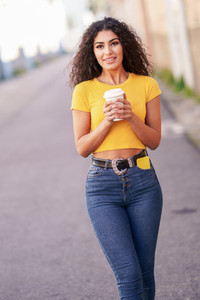 Arab girl walking across the street with a take away coffee