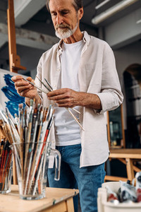 Male artist choosing paintbrush