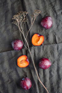 High angle view of fresh purple plum on a dark linen Food photography still life