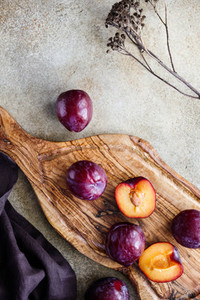 High angle view of fresh purple plum on a textured wooden cutting board