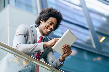 Black Businessman using a digital tablet sitting near an office building