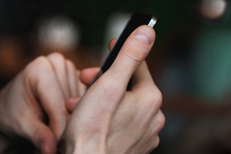 Close up of mans hands holding smartphone Blurred background